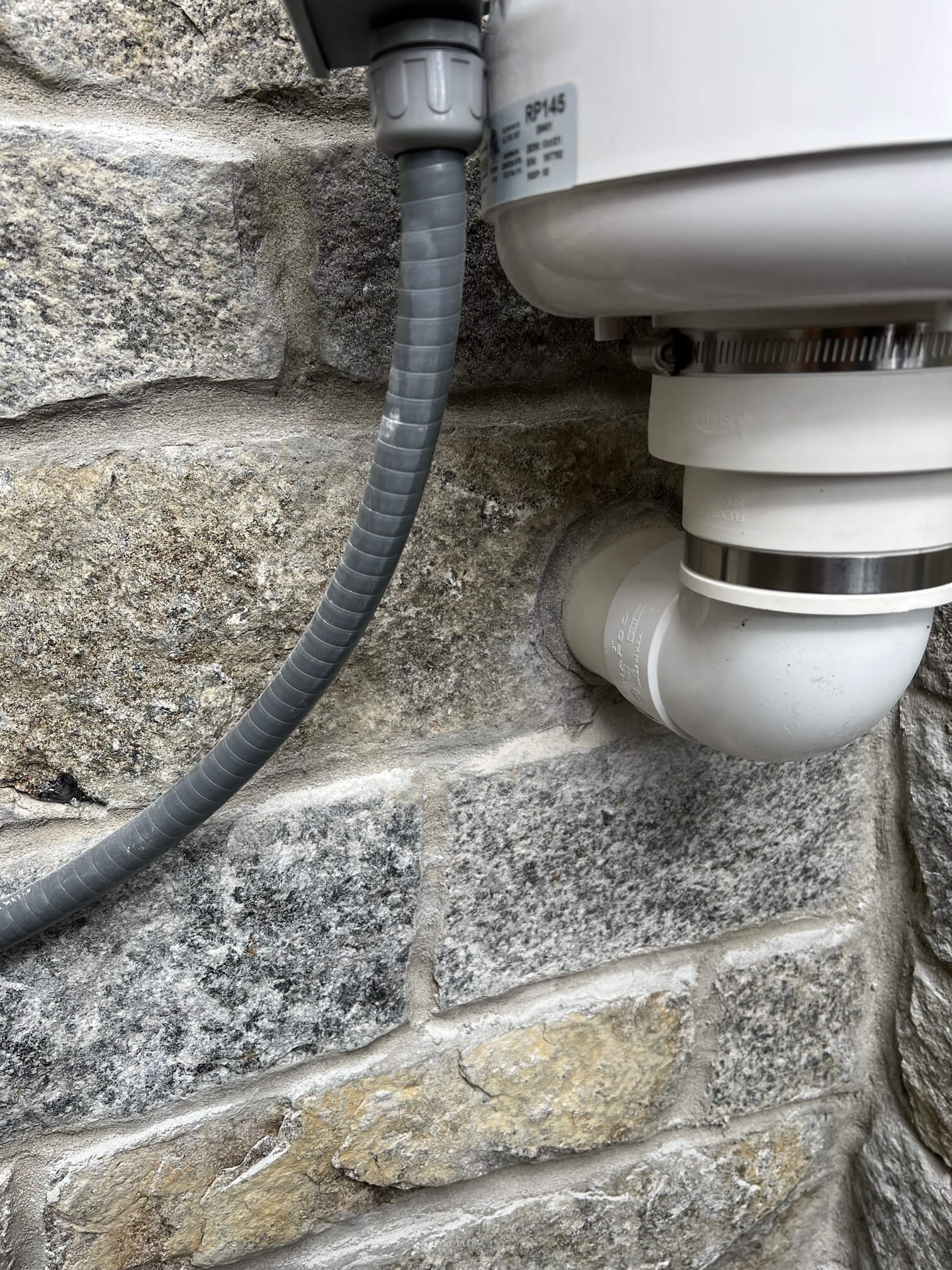 Radon mitigation fan installed on the exterior of a brick house